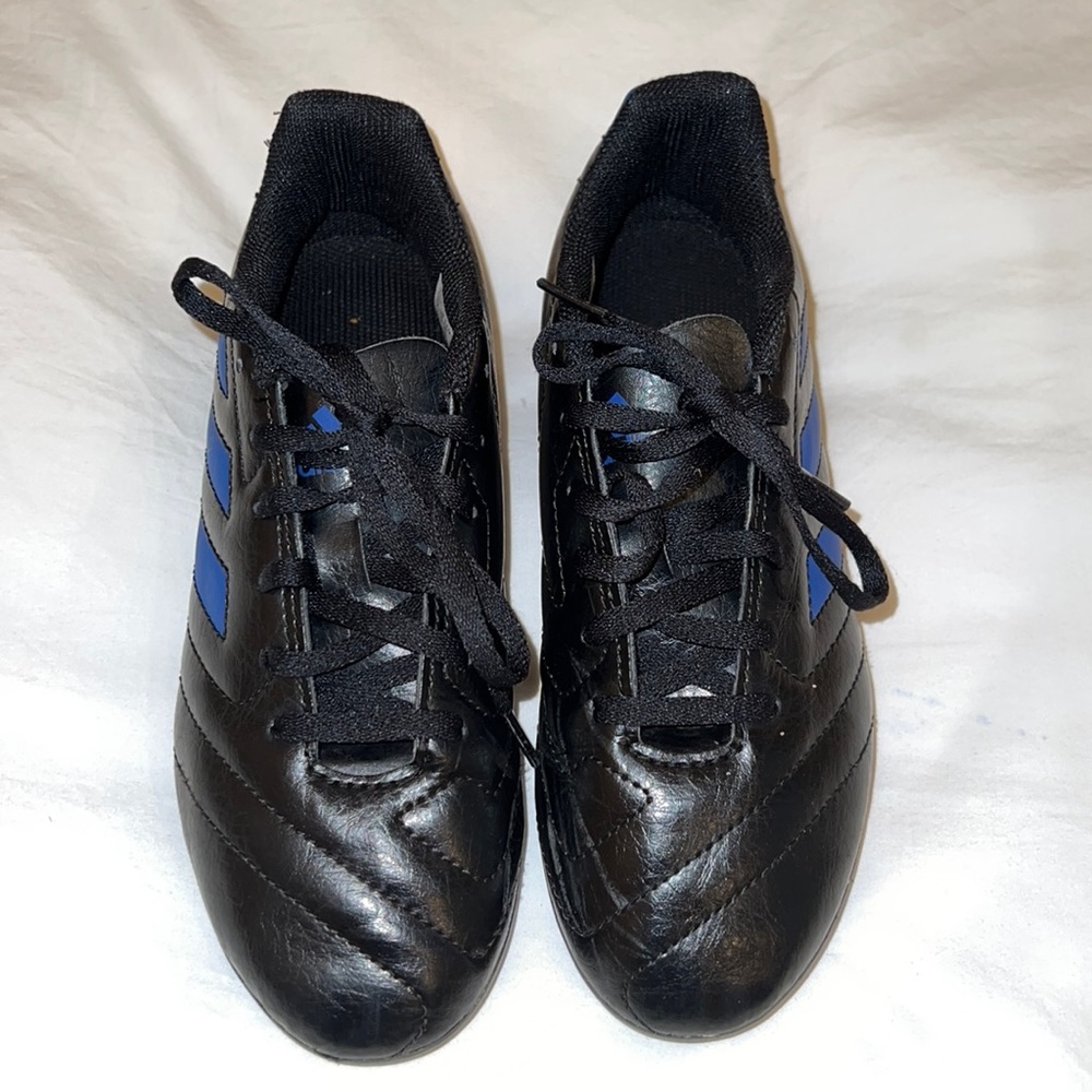 Black Adidas cleats with blue stripes.